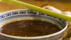 a blue and white bowl filled with soup next to sliced ginger