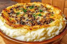 mashed potatoes topped with mushrooms and parsley in a wooden bowl on a table