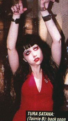 a woman with her hands up in the air while wearing red shirt and black bracelets