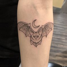 a bat tattoo on the arm with a crescent moon in the middle and an intricate design