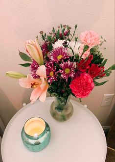 a vase filled with flowers sitting on top of a table next to a lit candle