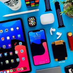 an assortment of electronics and gadgets laid out on a blue surface, including two ipads