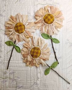 three sunflowers made out of paper on a quilt