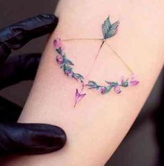 a woman's arm with an arrow and flowers on it