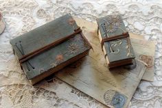 two small notebooks sitting on top of an old lace doily covered tablecloth