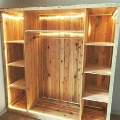 an empty wooden shelf with shelves and lights on it's sides, in the corner of a room