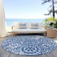 a large blue and white rug on top of a wooden floor next to a couch