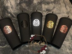 five starbucks coffee cups with gold and black designs on the sides, sitting next to each other