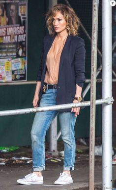 a woman is standing on the street with her hand in her pockets and looking off to the side