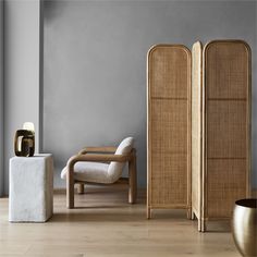 a room divider in the middle of a wooden floor next to a chair and vase