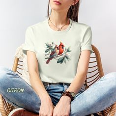 a woman sitting in a wicker chair wearing a t - shirt with a bird on it