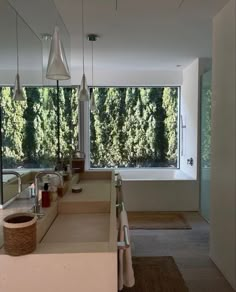 a bathroom with a large window, sink and bathtub in front of the trees