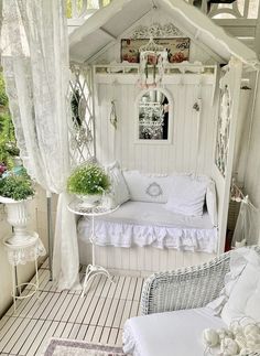 a white couch sitting under a window next to a potted plant