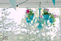 blue chandelier with flowers hanging from it's sides in front of a window