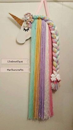 a unicorn head hanging from the side of a wall with rainbow hair and braids on it