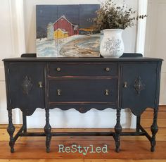 an old dresser is painted black and has a painting on it