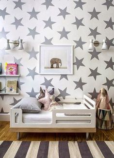 a child's bedroom with stars painted on the wall, and a bed in front of it