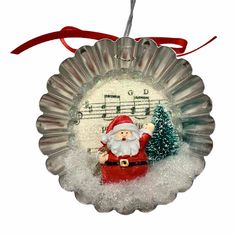 a glass ornament with a santa clause holding a christmas tree and music notes