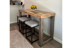 a wooden table with three stools and a vase filled with sunflowers on top