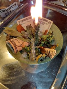 a lit candle on top of a plate filled with money