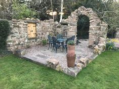 an outdoor dining area with stone walls and green grass