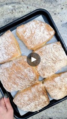 a person holding a pan filled with pastries on top of a marble countertop