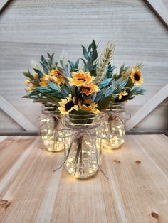 sunflowers and greenery in mason jars with string lights on a wooden table