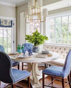 a dining room table with blue chairs and a vase on it's centerpiece