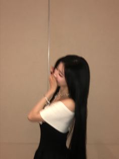 a woman with long black hair standing in front of a mirror