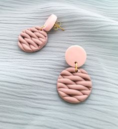 two pink and gold earrings sitting on top of a bed