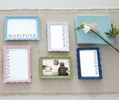 four different colored frames with flowers and pictures on them sitting on a table cloth next to each other