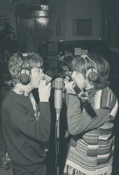 two people standing next to each other in front of a microphone with headphones on