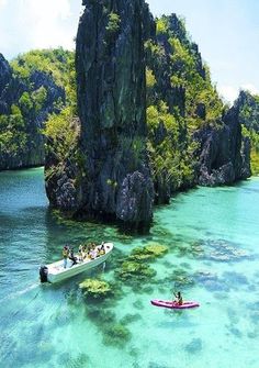 two boats in the water with people on them near some rocks and green vegetation,