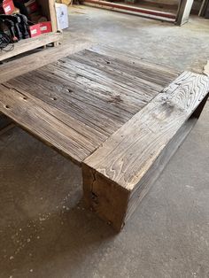 a wooden table sitting in the middle of a room next to a pile of boxes