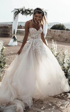 a woman in a wedding dress standing on the ground