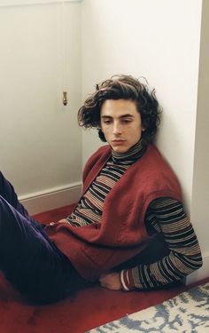 a young man sitting on the floor with his feet propped up in front of him