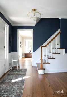 an empty hallway with blue walls and white railings, hardwood floors, and a rug on the floor