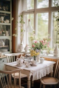 a table with flowers in vases on it next to two chairs and a window