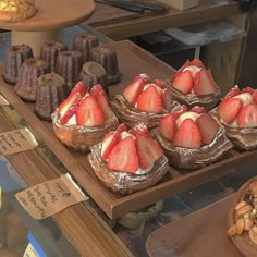 several pastries and desserts on display in a bakery case, including strawberries