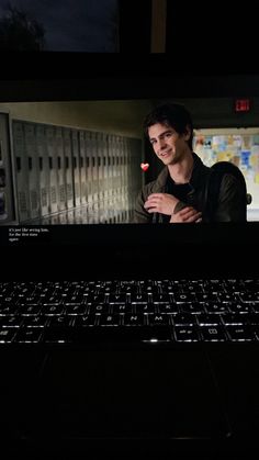 a man standing in front of a laptop computer with the screen showing an image of himself