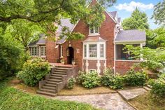 a red brick house surrounded by trees and bushes