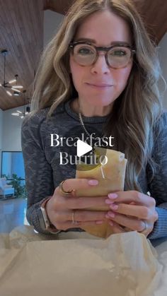 a woman wearing glasses holding a sandwich in her hands