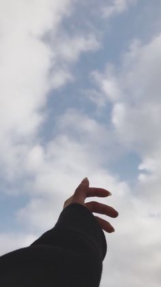 a hand reaching up into the sky to catch a frisbee