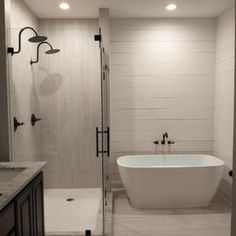 a white bath tub sitting inside of a bathroom next to a walk in shower stall