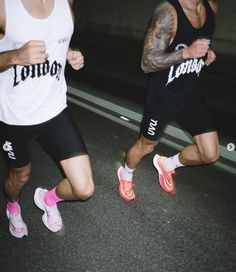 two men running in the street at night with one wearing pink and white shoes, while the other is black