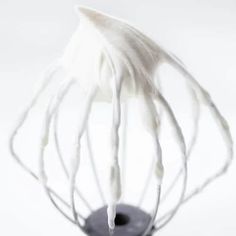 a whisk is being held up in the air with white icing on it