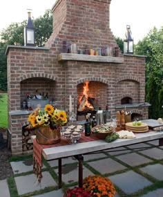 an outdoor brick oven with food on the table and flowers in pots next to it