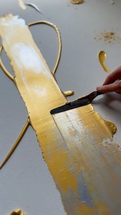 a person is painting gold paint on a piece of metal