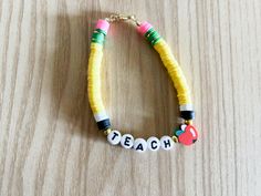 a necklace made out of plastic beads with words teach and an apple on the bead