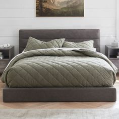 a bed with a quilted comforter and pillows on top of it in a room